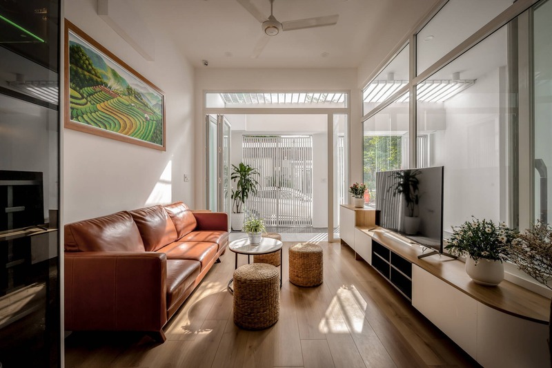 Không gian phòng khách với sofa, tủ kệ, các bức tranh treo tường đều được bố trí theo chiều dọc giúp không gian như được nới rộng ra
